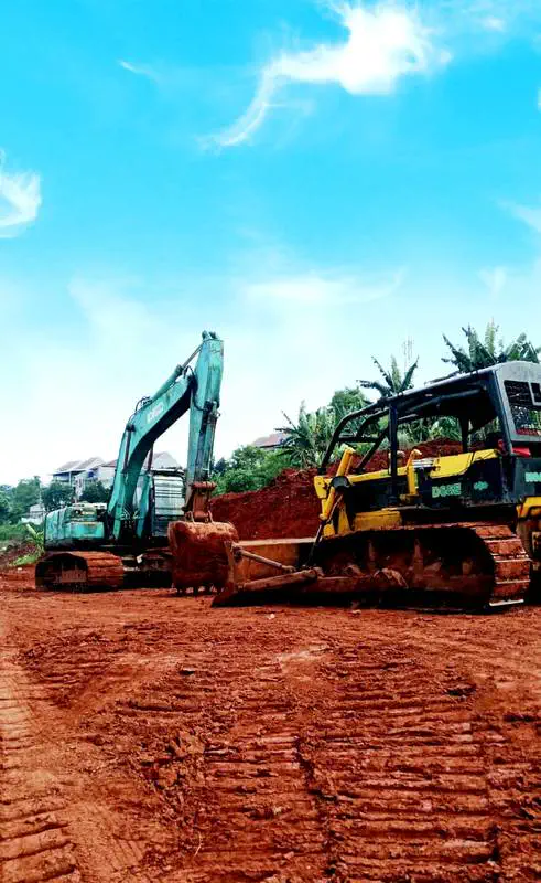 Excavator dan bulldozer bekerja bersama di pematangan lahan